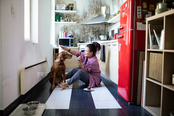 Woman celebrating dogs birthday with a cupcake and party hat in the kitchen