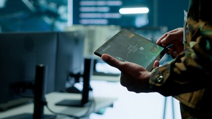 Military officer leads cybersecurity operations in a high tech operation room command post,...