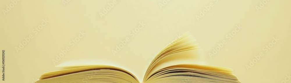 Poster Open Book with Pages Curving Upwards on a Light Yellow Background