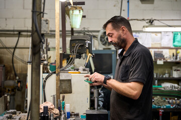 Metalworker measuring custom mechanical parts in metallurgy fabric workshop