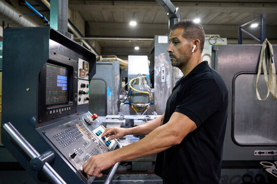 Metalworker operating cnc machine in factory: manufacturing process