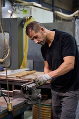 Metalworker shaping metal part using bench vise in workshop