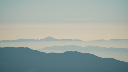Fototapeta premium Generative AI, Minimalist Aerial View of Serene Mountain Ranges with Soft Cloud Layers