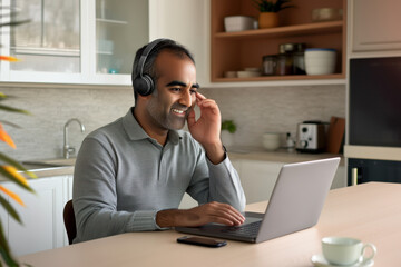 Man working from home, attending a video call on laptop with headphones - remote work and virtual communication concept