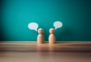 Naklejka premium Two wooden figures stand facing each other with blank speech bubbles above their heads.