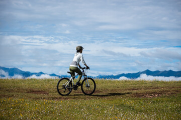 Obraz premium Asian woman riding mountain bike on beautiful mountain top