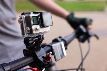 Man riding bicycle with modern action camera outdoors, closeup