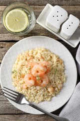 Delicious risotto with shrimps and cheese served on wooden table, top view