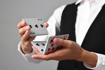 Professional croupier shuffling cards on grey background, closeup