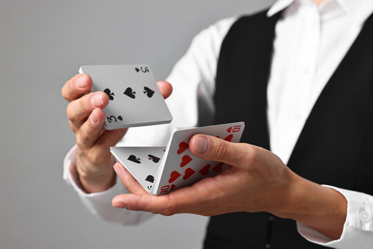 Professional croupier shuffling cards on grey background, closeup