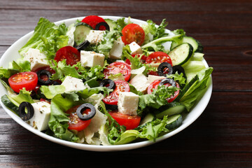 Delicious salad with feta cheese on wooden table, closeup