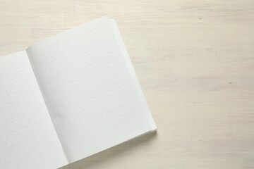 Book with Braille text on wooden table, top view. Space for text