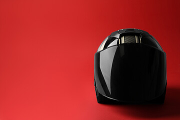 Modern motorcycle helmet with visor on red background, space for text