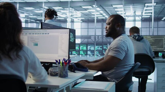 Engineer writing code and doing checkup on server room providing computing resources for different workloads. Man investigating data center mainframes using computer, camera B