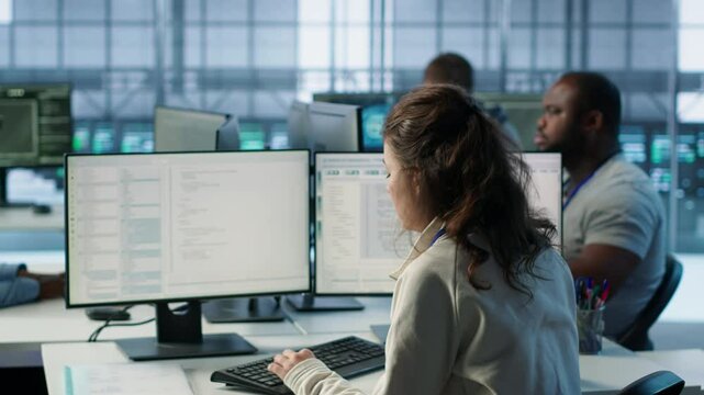 Manager overseeing server room holding impromptu meeting with employees. Supervisor in server hub, asking for attention to offer feedback to workers after doing inspection, camera A