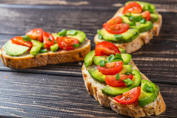 Avocado toast topped with tomato and green onion on a slice of carrot bread