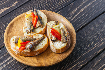 fish sandwich with butter and sprats lemon and red pepper on a dark table