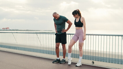 Multiethnic male and female athletes in summer exercises before running next to the sea, enjoy teamwork, couple goals. Happy fit people are cheerfully doing sports