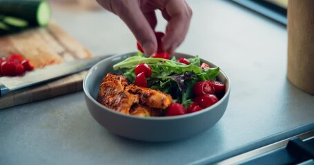 Person, hands and bowl with salad for meal, snack or healthy diet on table in kitchen at home. Closeup, chef or cook with tomatoes, vegetables or vegan cuisine for vitamins, nutrition or house recipe