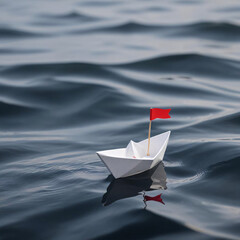 A paper boat with a red flag on it is floating in the water