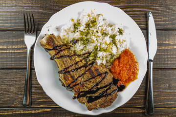 steak entrecote on the bone with rice and vegetables on a white plate top view