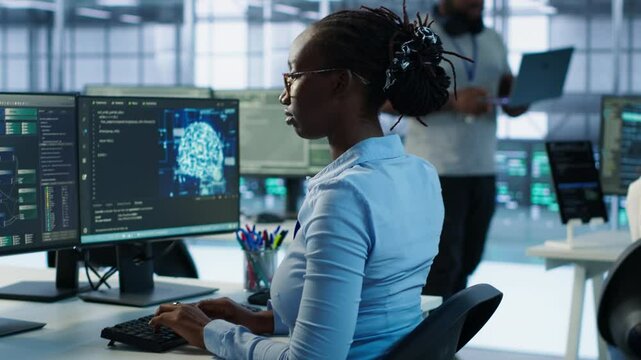 Manager coming to technician desk to give instructions on doing maintenance on artificial intelligence neural networks. Supervisor overseeing worker using AI system software, camera A