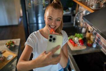 Young woman filming cooking tutorial in kitchen with fresh vegetables and eggs