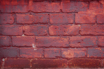 A fragment of a red brick wall with pronounced texture. Natural age defects in the form of cracks and abrasions. Rough surface with traces of dried paint.