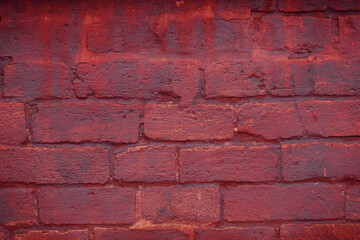 A fragment of a red brick wall with pronounced texture. Natural age defects in the form of cracks and abrasions. Rough surface with traces of dried paint.