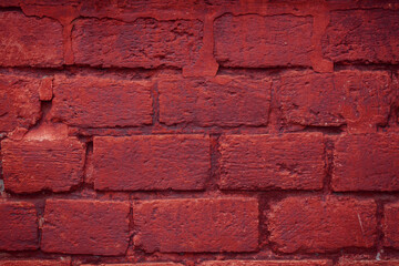 Obraz premium A fragment of a red brick wall with pronounced texture. Natural age defects in the form of cracks and abrasions. Rough surface with traces of dried paint.