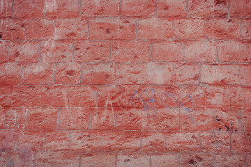 A fragment of a red brick wall with pronounced texture. Natural age defects in the form of cracks and abrasions. Rough surface with traces of dried paint.