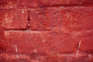 A fragment of a red brick wall with pronounced texture. Natural age defects in the form of cracks...