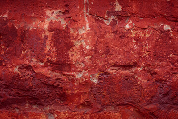 A fragment of a red brick wall with pronounced texture. Natural age defects in the form of cracks and abrasions. Rough surface with traces of dried paint.