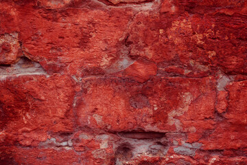 A fragment of a red brick wall with pronounced texture. Natural age defects in the form of cracks...