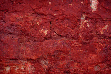 A fragment of a red brick wall with pronounced texture. Natural age defects in the form of cracks and abrasions. Rough surface with traces of dried paint.