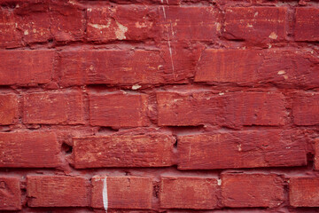 Obraz premium A fragment of a red brick wall with pronounced texture. Natural age defects in the form of cracks and abrasions. Rough surface with traces of dried paint.