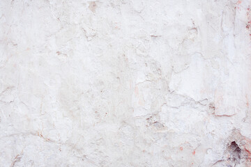 Grey concrete wall with natural defects. Fragment of the cement surface with natural texture. Natural cracked plaster on a light wall. Textured background for integration into the design.