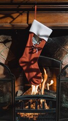 A single festive red and white Christmas stocking, featuring a cozy holiday pattern, hangs dramatically illuminated on a dark wooden mantlepiece.