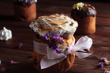 Easter cake on the festive table. Festive pastries with riotous spring colors against a dark wood background. Dried flowers in decorative compositions. Decor in swirled eggnog with dark caramel.