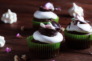 Easter cake on the festive table. Festive pastries with wild spring colors on a dark wood background. Dried flowers in decorative compositions. Decor in the form of a nest with dragon eggs.