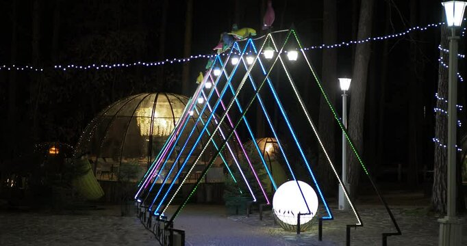 Night city. Burning lanterns in the form of a hut are placed above the sidewalk that leads to a transparent igloo. Hand held. Siberia.