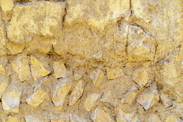 yellow ancient crack cement wall or retro old golden stones and broken dry soil mud or rock background to rough surface stucco concrete and gold paint for texture backdrop and floor pattern wallpaper