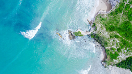 Aerial drone view of turquoise sea water meeting a rocky coastline on a sunny summer day © Balnyes Visuals