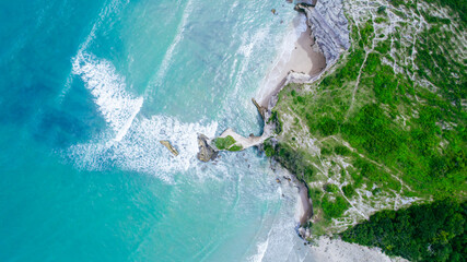 Aerial view of blue sea, rocks in clear water, beach, green trees in summer © Balnyes Visuals