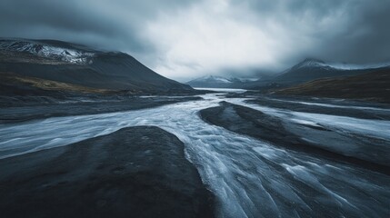 A dramatic, moody shot of a river winding through a glacial valley, with snow-capped mountains and a stormy sky in the background.
