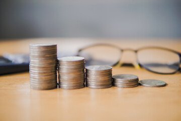 Stack money coins with glasses and calculator background. Money financial planning concept. Saving money and investing is growing wealthy and sustainable for the future concept.