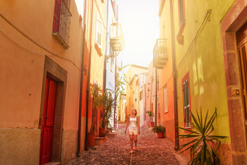 Female traveler walking through the streets of Bosa