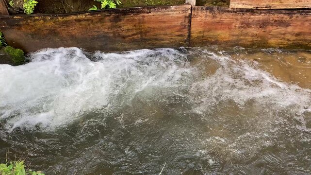 Close up view of river currents or water ripples. Clear fresh water flowing with wooden edge