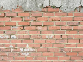 Obraz premium Weathered and textured red brick wall with patches of moss and cracks, worn, red brick, textured