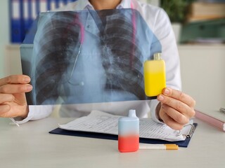 Doctor holds vape and X-ray lungs. Consequences of smoking vape electronic cigarettes